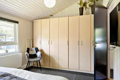 a bedroom with a bed and a chair and cabinets at BL1566-Saltum-Lille-Fiskerbanke-3 in Saltum