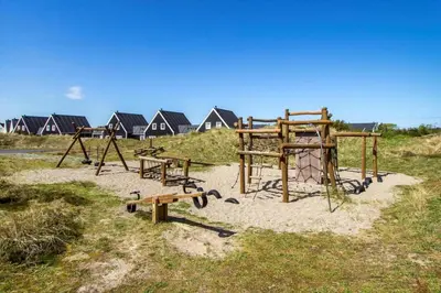 a park with benches and a playground with houses in the background at BL1401-Blokhus-Ferren-Syd-78 in Blokhus