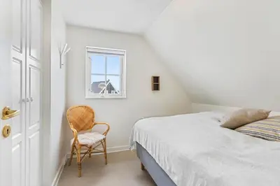 a bedroom with a bed and a chair and a window at BL1401-Blokhus-Ferren-Syd-78 in Blokhus