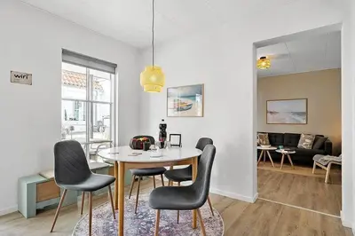 a dining room with a table and chairs in a living room at BL1582-Blokhus-Strandvejen-14-Lejl-11 in Blokhus