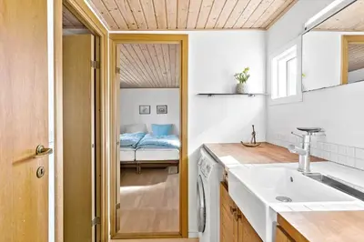 a bathroom with a sink and a bed in a room at BL1548-Blokhus-Paa-Bakken-10 in Blokhus