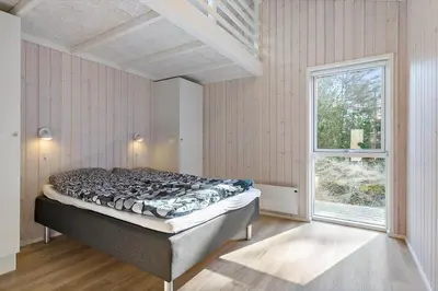 a bedroom with a bed in a room with a window at BL1783-Blokhus-Lyngbakkevej-9 in Blokhus