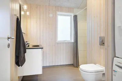 a bathroom with a toilet and a sink and a window at BL1783-Blokhus-Lyngbakkevej-9 in Blokhus
