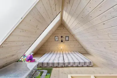a room in a wooden house with a bed in the attic at BL1775-Pandrup-Rodhus-Klitvej-335 in Pandrup