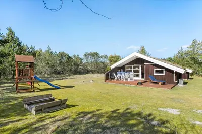 a log cabin with a slide and a playground at BL224-Pandrup-Rodhusparken-91 in Pandrup