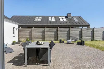 a patio with a table and chairs in front of a house at BL509-Blokhus-Jens-Baerentsvej-7 in Blokhus