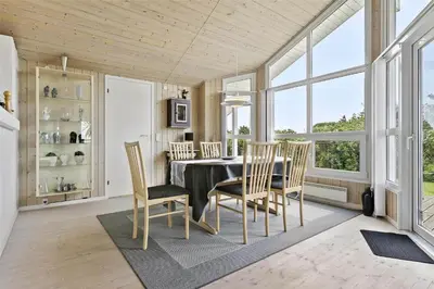 a dining room with a table and chairs and windows at BL314-Blokhus-Bakkevaenget-5 in Blokhus