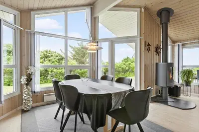 a dining room with a table and chairs and windows at BL314-Blokhus-Bakkevaenget-5 in Blokhus