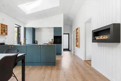 a kitchen with blue cabinets and a tv on a wall at BL1485-Blokhus-Jaegervaenget-2-A in Blokhus