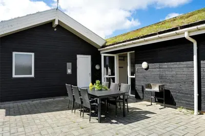 a black house with a table and chairs on a patio at BL1633-Saltum-Nordvestvej-18 in Saltum