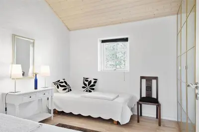 a white bedroom with two beds and a chair at BL1588-Pandrup-Lunen-88 in Pandrup