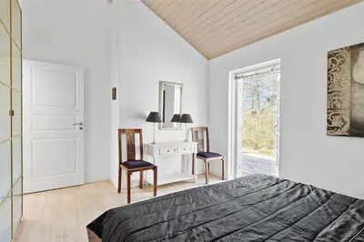 a bedroom with a bed and a mirror and a door at BL1588-Pandrup-Lunen-88 in Pandrup