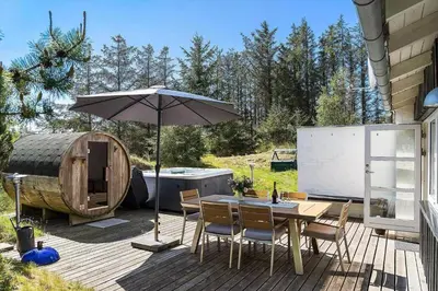 a wooden deck with a table and an umbrella at BL1420-Blokhus-Ronliensvej-21 in Blokhus