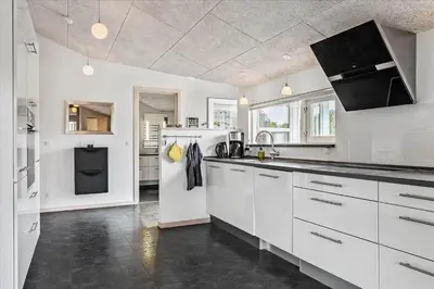 a kitchen with white cabinets and a black counter top at BL1492-Blokhus-Plantagevej-19-B in Blokhus