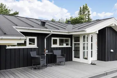a black house with a white roof and a deck at BL1492-Blokhus-Plantagevej-19-B in Blokhus