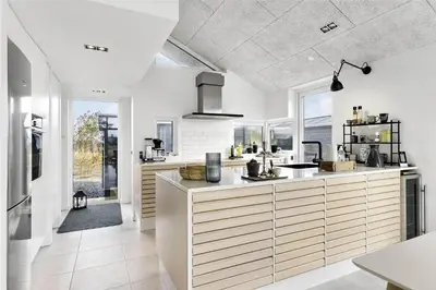 a large kitchen with white walls and a large island at BL1667-Blokhus-Klitvejen-24 in Blokhus