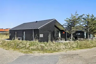 a black house sitting on the side of a road at BL1667-Blokhus-Klitvejen-24 in Blokhus
