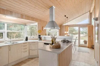 a kitchen with a large island in a room with windows at BL1426-Blokhus-Morten-Nielsensvej-86 in Blokhus