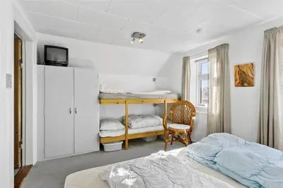 a bedroom with two beds and a tv and a chair at BL327-Blokhus-Sonder-I-By-23 in Blokhus
