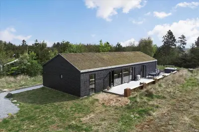 a small black house on top of a hill at BL1513-Blokhus-Gyldenrisvej-18 in Blokhus