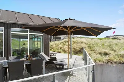 a patio with a table and an umbrella at BL1468-Blokhus-Moreavej-59-B in Blokhus
