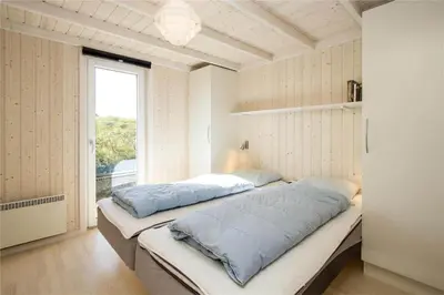 a bedroom with a bed with blue pillows on it at BL289-Blokhus-Moreavej-41 in Blokhus