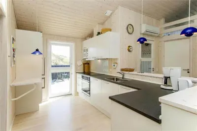 a kitchen with white cabinets and a black counter top at BL289-Blokhus-Moreavej-41 in Blokhus