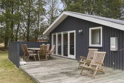 a black shed with chairs and a table on a deck at BL489-Pandrup-Rodhusparken-24 in Pandrup