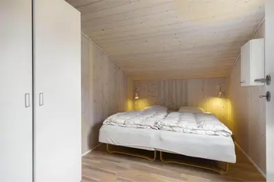a bed in a room with a wooden ceiling at BL489-Pandrup-Rodhusparken-24 in Pandrup