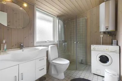 a bathroom with a toilet and a sink and a washing machine at BL489-Pandrup-Rodhusparken-24 in Pandrup