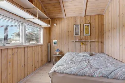 a bedroom with a bed in a wooden wall at BL1378-Blokhus-Klitvejen-65 in Blokhus
