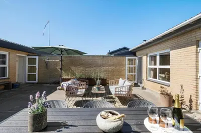 a patio with a table and chairs and an umbrella at BL1209-Blokhus-Bellevueparken-14 in Blokhus