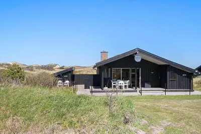 a black house with some chairs in front of it at BL1497-Pandrup-Hunetorp-Klitvej-271 in Pandrup