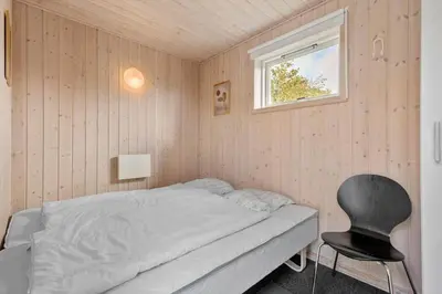 a small bedroom with a bed and a chair at BL497-Saltum-Tolhoj-4 in Saltum