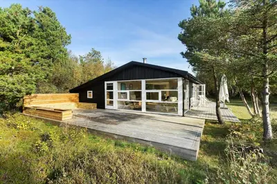 a black house with a deck in a field at BL1589-Saltum-Bondagervej-52 in Saltum