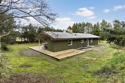a small green cabin with a deck in a field at BL1786-Saltum-Ornebjergvej-22 in Saltum
