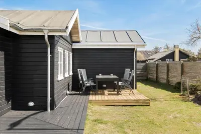 a black shed with a table and chairs on a deck at BL395-Blokhus-Maren-Hjortelsvej-4 in Blokhus