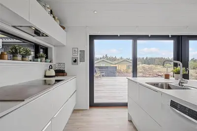 a kitchen with white counters and a large window at BL1740-Blokhus-Axel-P-Jensenvej-19 in Blokhus