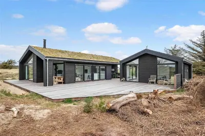a black house with a deck on the beach at BL1740-Blokhus-Axel-P-Jensenvej-19 in Blokhus
