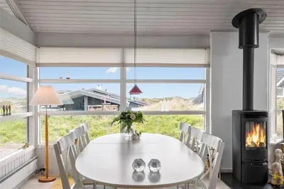 a dining room with a white table and a fireplace at BL330-Blokhus-Lyngvej-2 in Blokhus