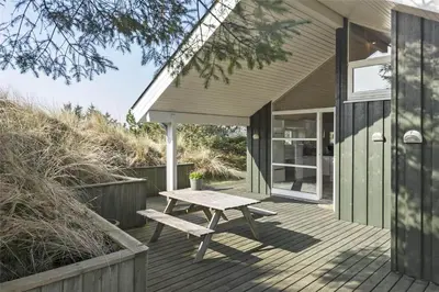 a wooden deck with a picnic table on a house at BL401-Blokhus-Lyngvej-12 in Blokhus