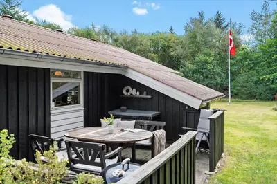 a black shed with a table and chairs and a flag at BL1338-Pandrup-Lunekrogen-10 in Pandrup