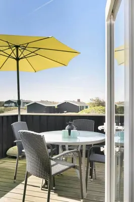 a patio with a table and chairs and an umbrella at BL1729-Blokhus-Jens-Baerentsvej-36 in Blokhus