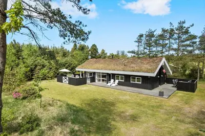 a black house with a grass roof on a yard at BL279-Pandrup-Rodhusparken-71 in Pandrup