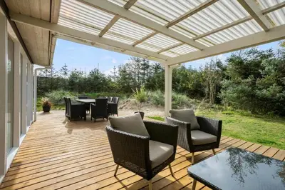 a wooden deck with chairs and a pergola at BL1774-Blokhus-Ronliensvej-11 in Blokhus