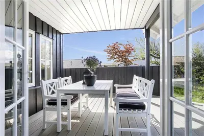 a white table and chairs on a porch with windows at BL475-Blokhus-Peder-Madsensvej-21 in Blokhus