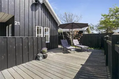 a wooden deck with two chairs and an umbrella at BL475-Blokhus-Peder-Madsensvej-21 in Blokhus