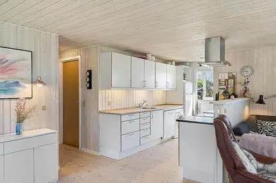 a kitchen with white cabinets and a couch in a room at BL1366-Blokhus-Berberisvej-56 in Blokhus
