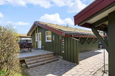 a green house with a porch and a patio at BL794-Pandrup-Hunetorp-Klitvej-113 in Pandrup