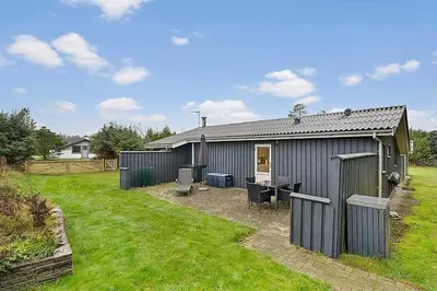 a gray shed with a desk in a yard at BL1451-Blokhus-Quintusvej-5 in Blokhus